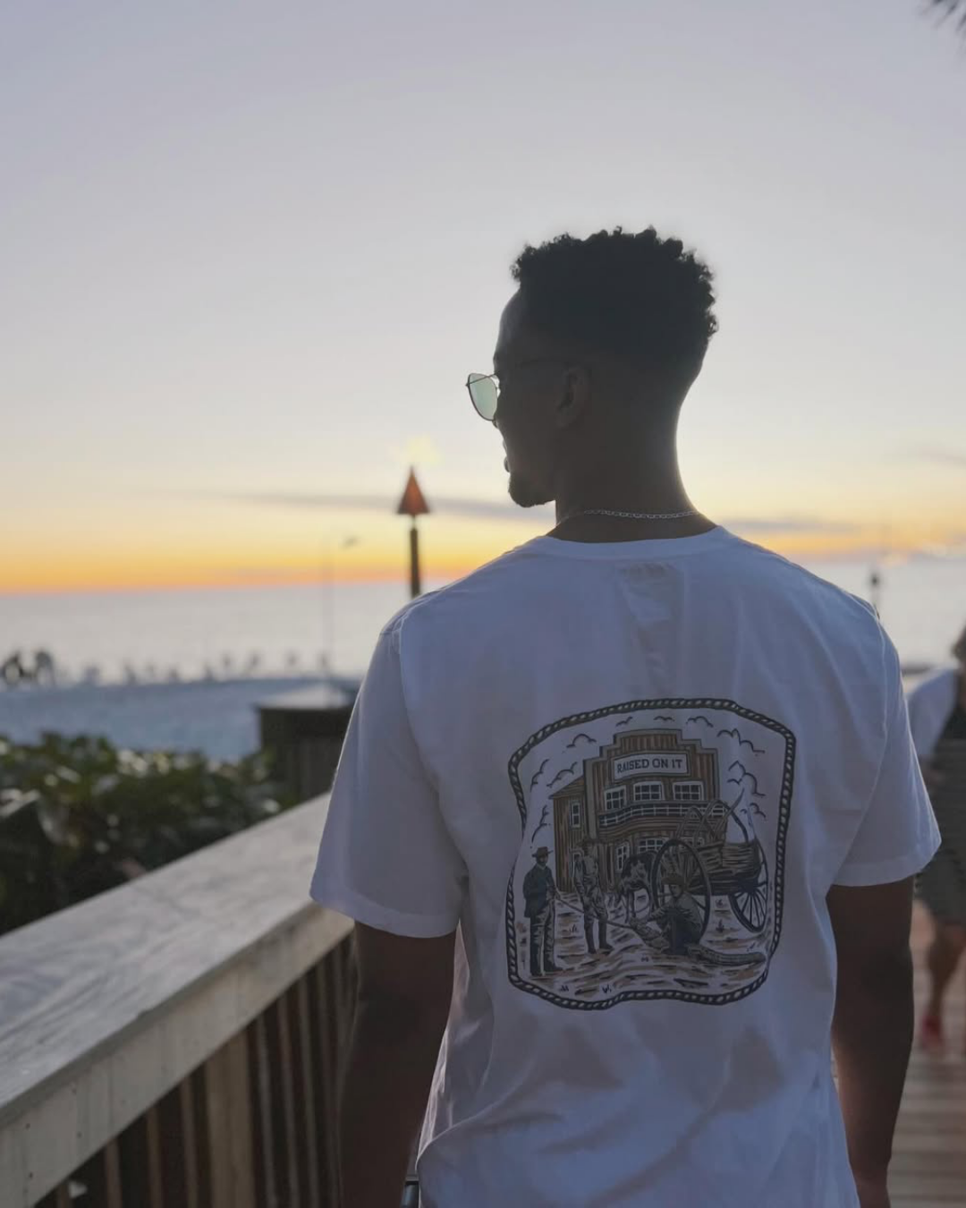 Back of the Florida Cowboy tee worn on a Florida beach boardwalk at sunset