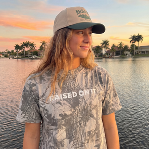 Woman wearing the Outboard Legacy Mudboat hat by the water at sunset