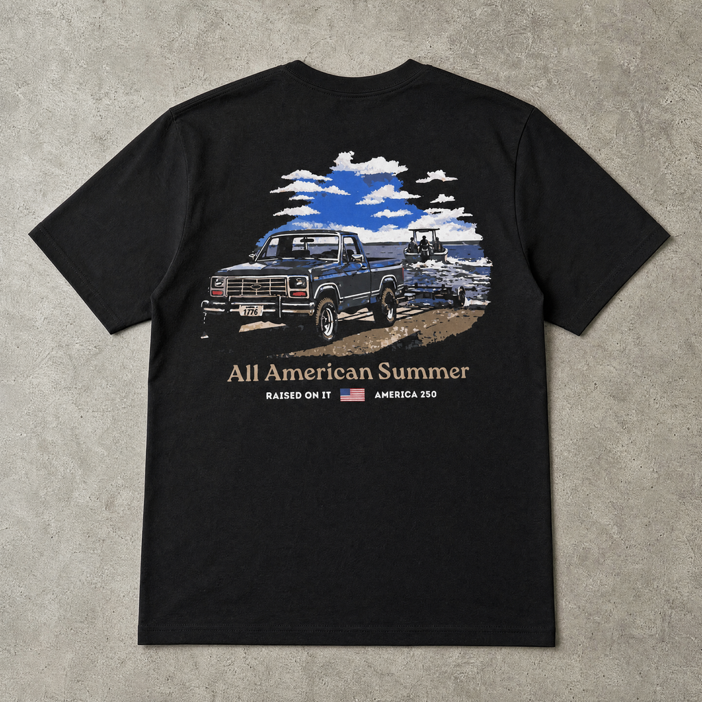 Raised On It All American Summer black tee back design, flat-lay on concrete